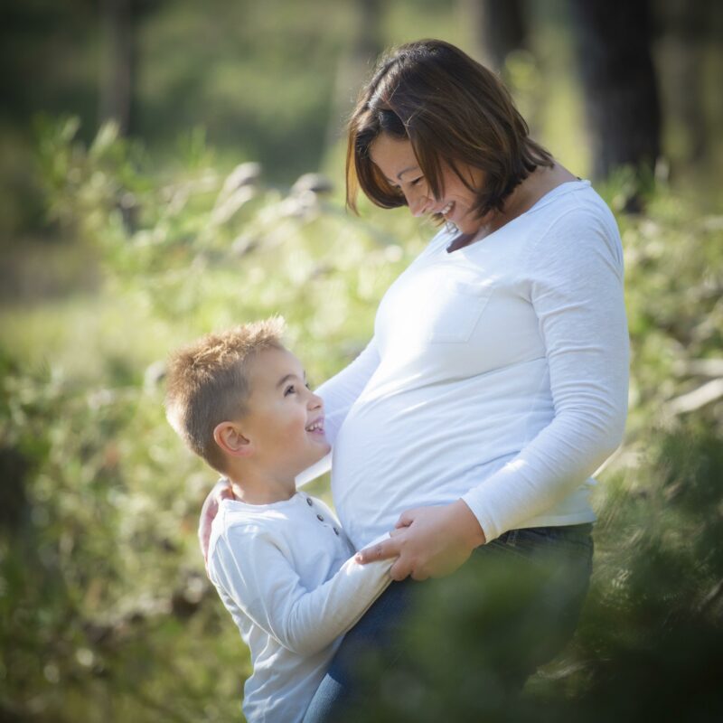 Portrait de femme enceinte avec un enfant dans ses bras en extérieur pour Lorie Diaz Photographe