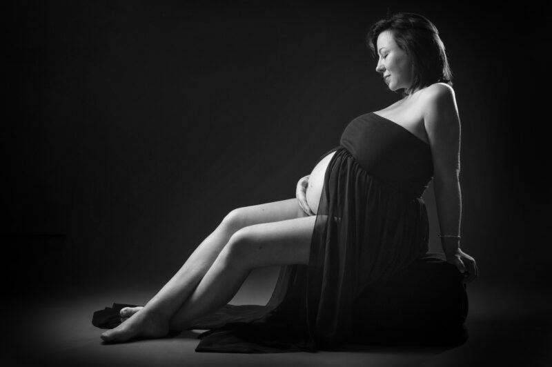 Portrait en noir et blanc de femme enceinte assise pour Lorie Diaz photographe