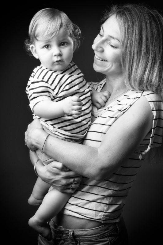 Portrait de famille en noir et blanc d'une mère avec son enfant dans les bras pour Lorie Diaz Photographe