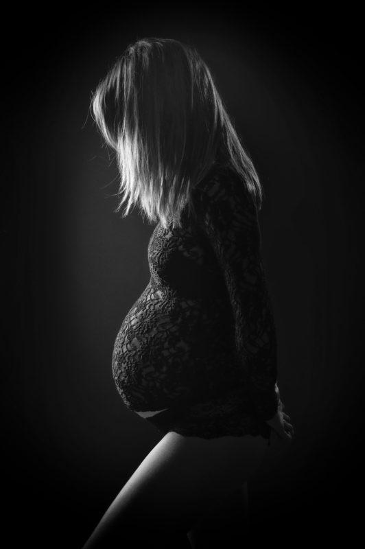 Femme enceinte en noir et blanc en studio en silhouette sur fond noir pour Lorie Diaz photographe