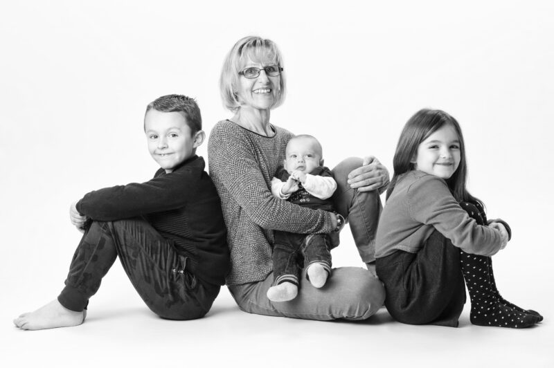 Portrait de famille d'une grand-mère avec ses petits-enfants en studio en noir et blanc sur fond blanc pour Lorie Diaz photographe